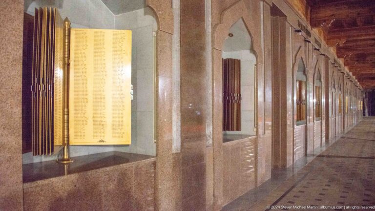 Golden memorial book displayed in a pointed-arch niche along a polished stone gallery.