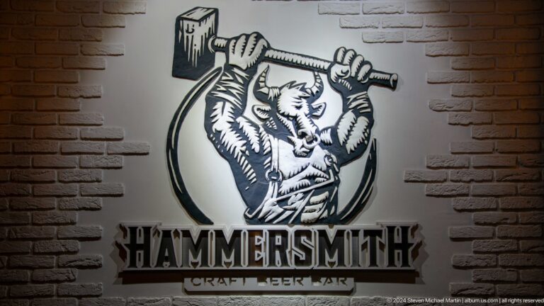 Black-and-white Hammersmith wall logo with a bearded worker raising a hammer.