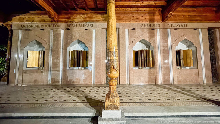 Golden memorial books in pointed wall niches beside a carved wooden column.