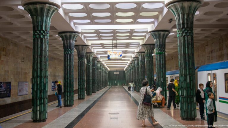 Long Kosmonavtlar Metro station hall with green columns, oval ceiling lights, and blue wall panels.