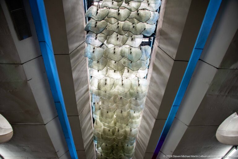 Upward view of a long illuminated ceiling feature made from overlapping translucent disks.