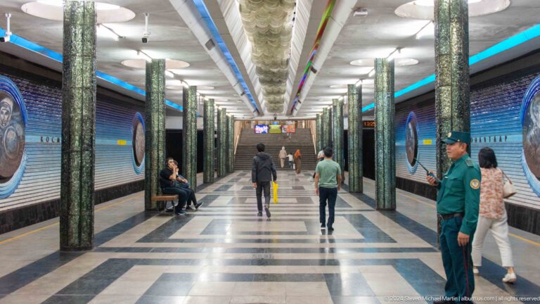 Long Kosmonavtlar station hall with green columns, blue walls, and stairs in the distance.