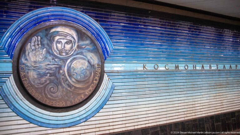 Round relief of helmeted cosmonaut Yuri Gagarin raising one hand beside a globe.