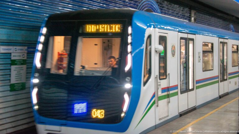 Modern blue-and-white Tashkent Metro train number 043 at a station platform.
