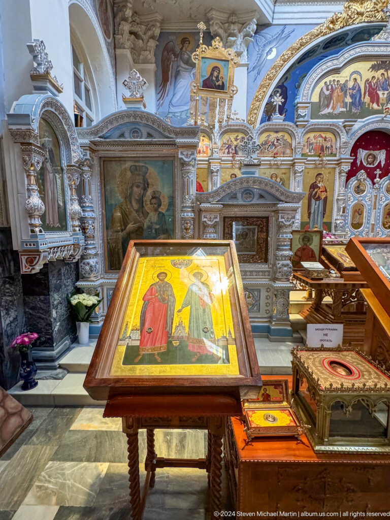 Icon of two haloed figures displayed on a sloped wooden stand inside the cathedral.
