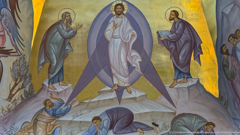 Mural of radiant Christ between two prophets above disciples on a mountain.