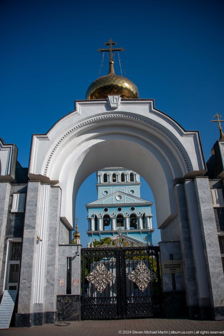 Large white entrance arch symmetrically framing the cathedral bell tower.