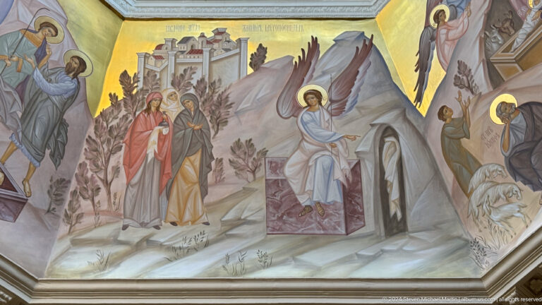 Mural of women approaching an empty tomb where an angel sits beside the open sarcophagus.