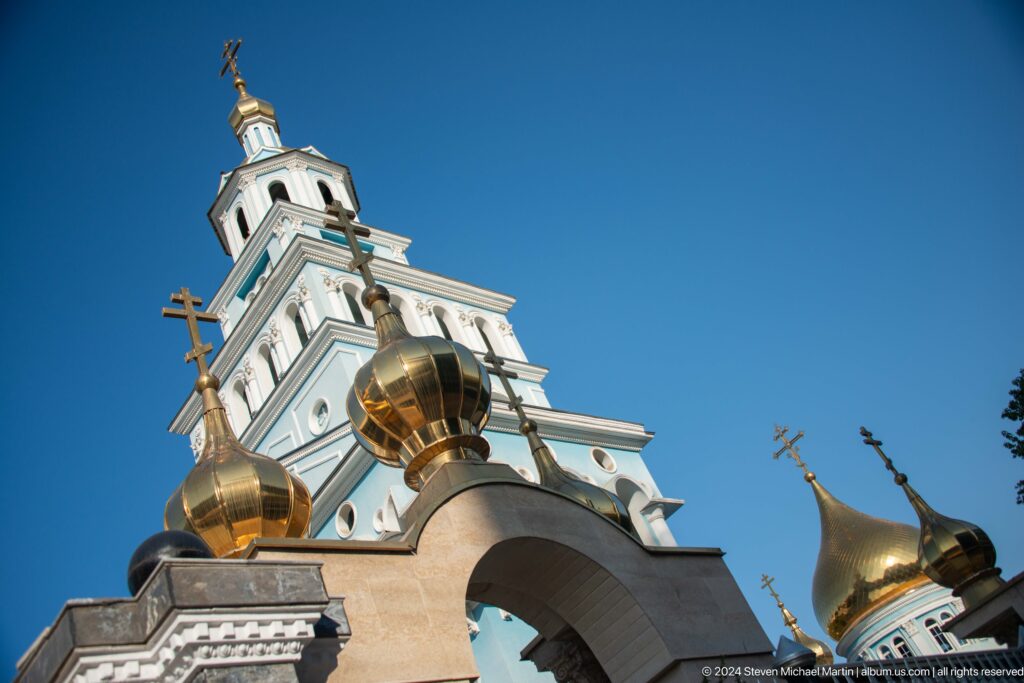 Low-angle view of several gilded onion domes and Orthodox crosses.