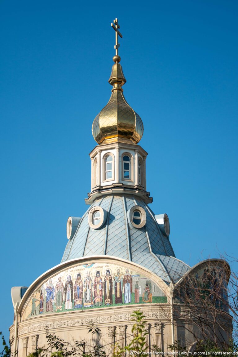Gilded onion dome above a pale blue faceted drum with arched and circular windows.