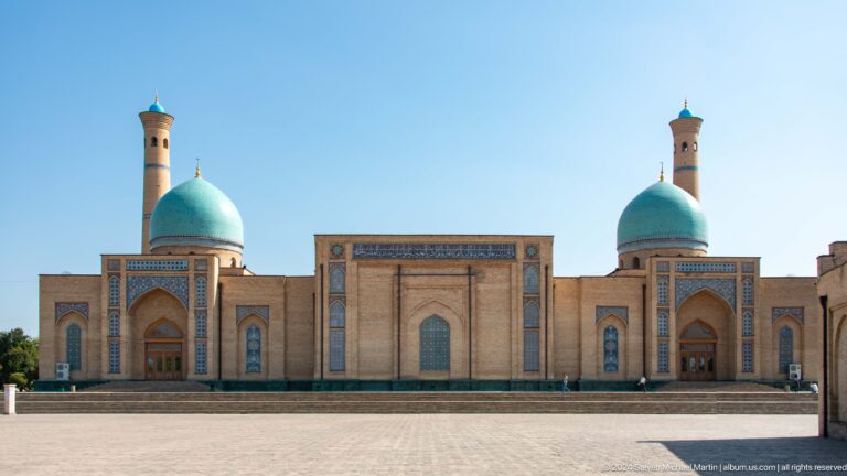 Broad symmetrical brick facade with two turquoise domes and twin minarets at the Khast Imom complex in Tashkent.