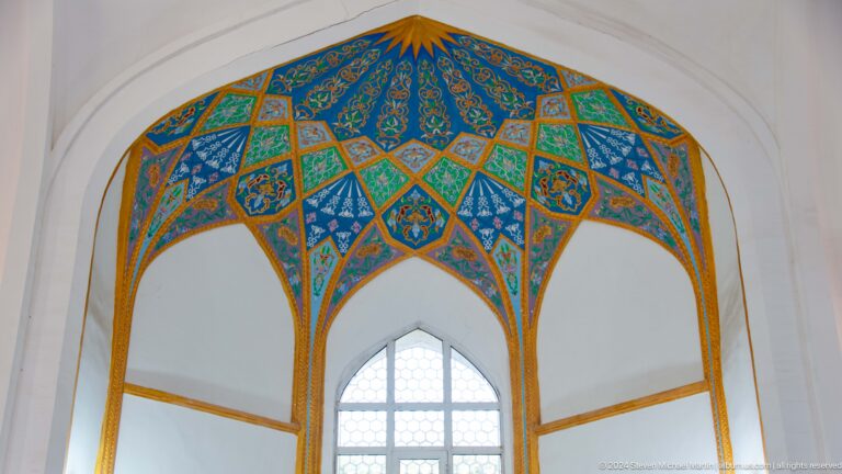 Blue, green, and gold geometric panels radiating around a white arched opening at the Khast Imom complex in Tashkent.