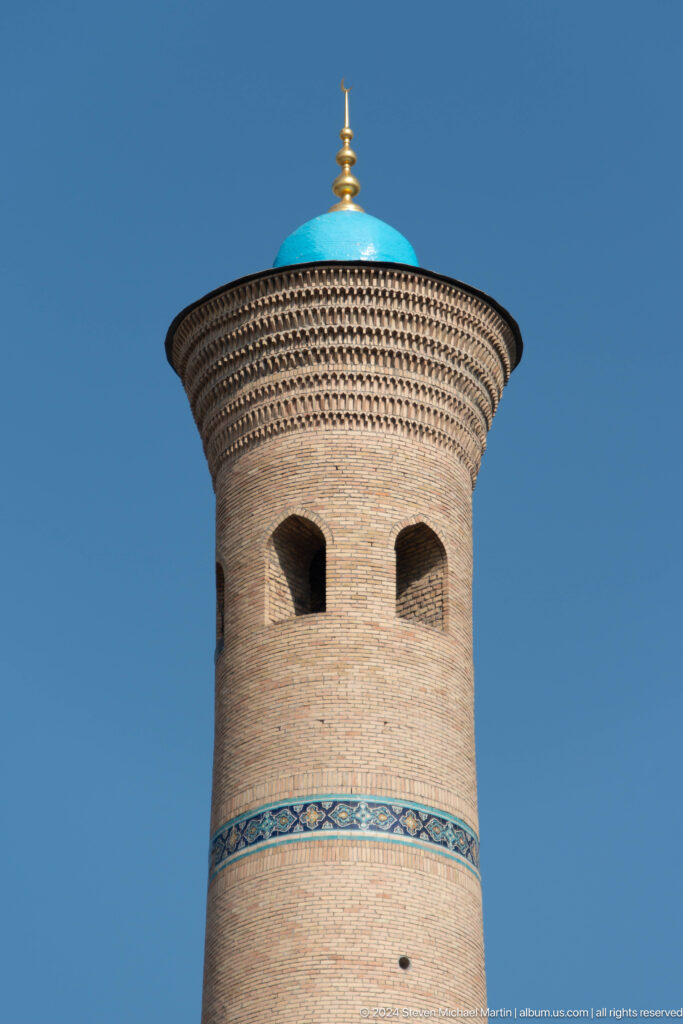 Brick tower crown with paired pointed openings and layered corbelled bands at the Khast Imom complex in Tashkent.