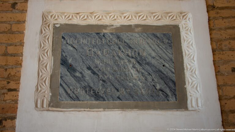 Rectangular gray slab with shallow lines of script in a carved white surround at the Khast Imom complex in Tashkent.