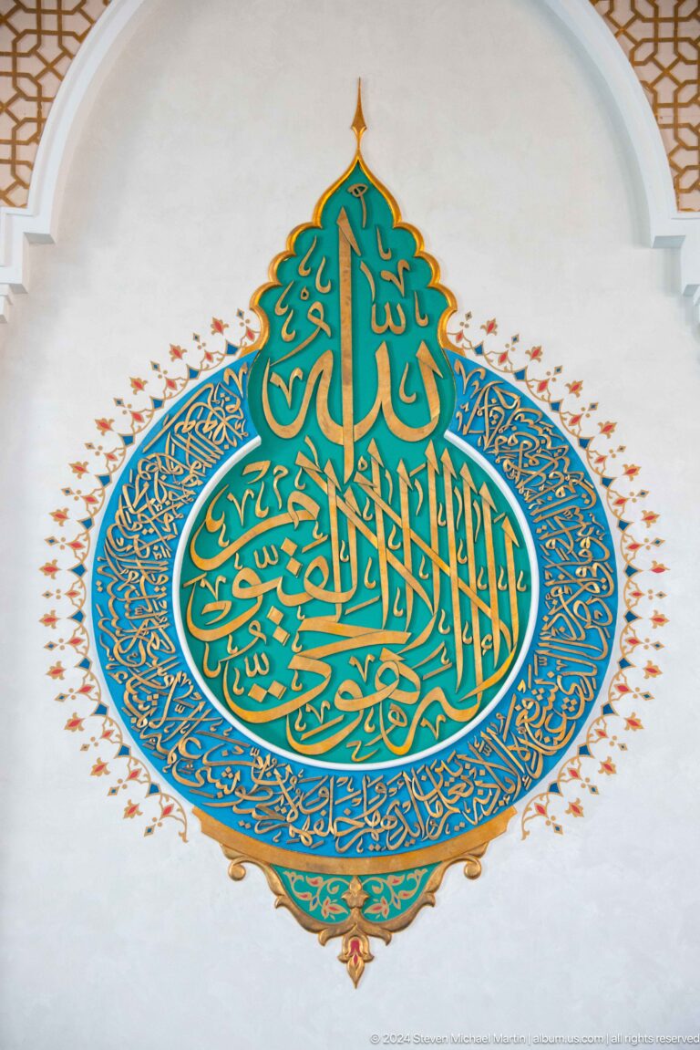 Large turquoise circular calligraphic composition outlined in gold on white wall at the Khast Imom complex in Tashkent.