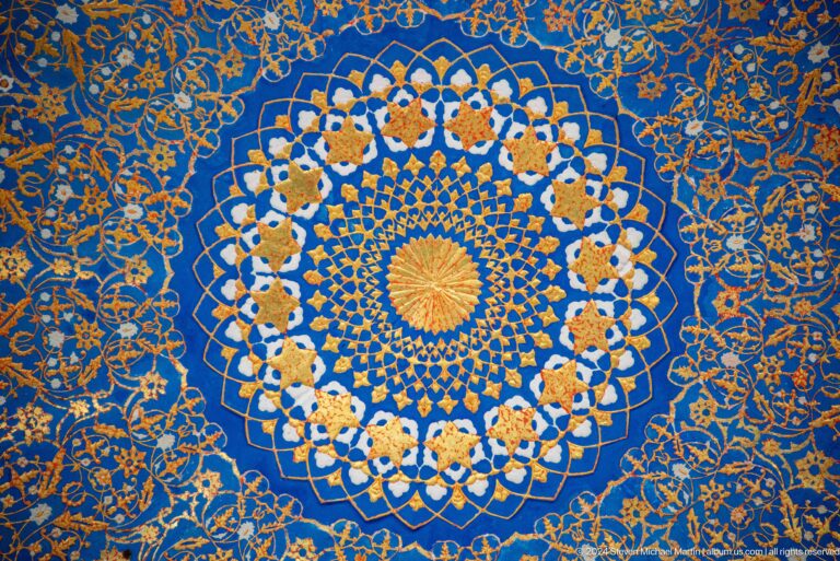 Circular yellow-centered rosette surrounded by interlaced white flowers on deep blue at the Khast Imom complex in Tashkent.