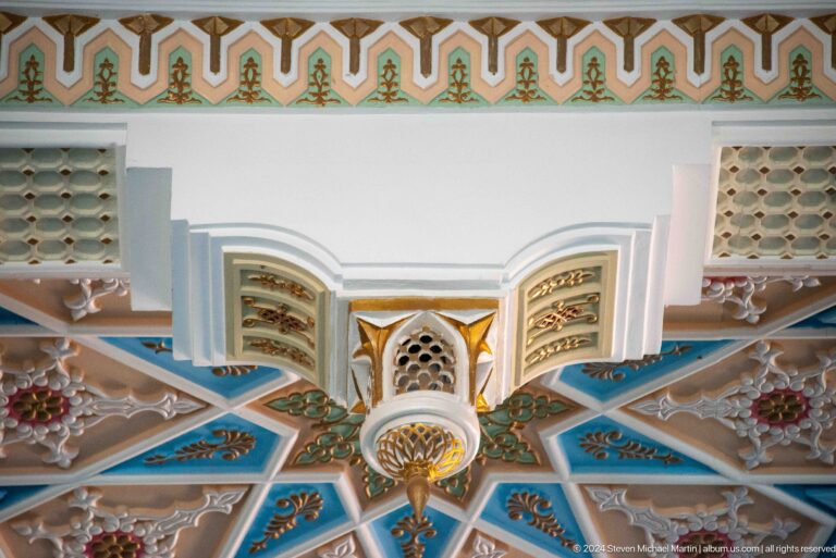 White carved projection beneath blue, green, and gold painted coffers at the Khast Imom complex in Tashkent.