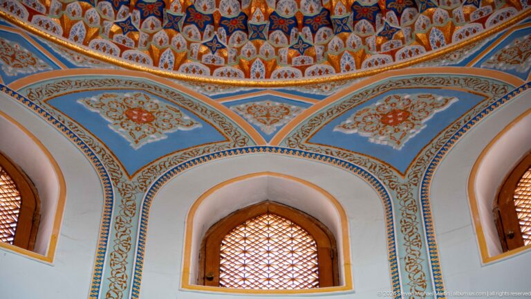 Arched opening edged by pale blue vegetal patterns and a red-and-gold frieze at the Khast Imom complex in Tashkent.
