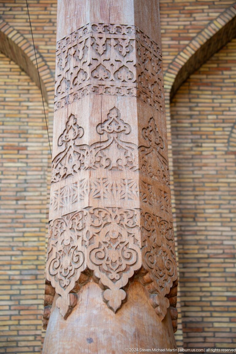 Close view of pale carved capital and shaft against tan brick wall at the Khast Imom complex in Tashkent.