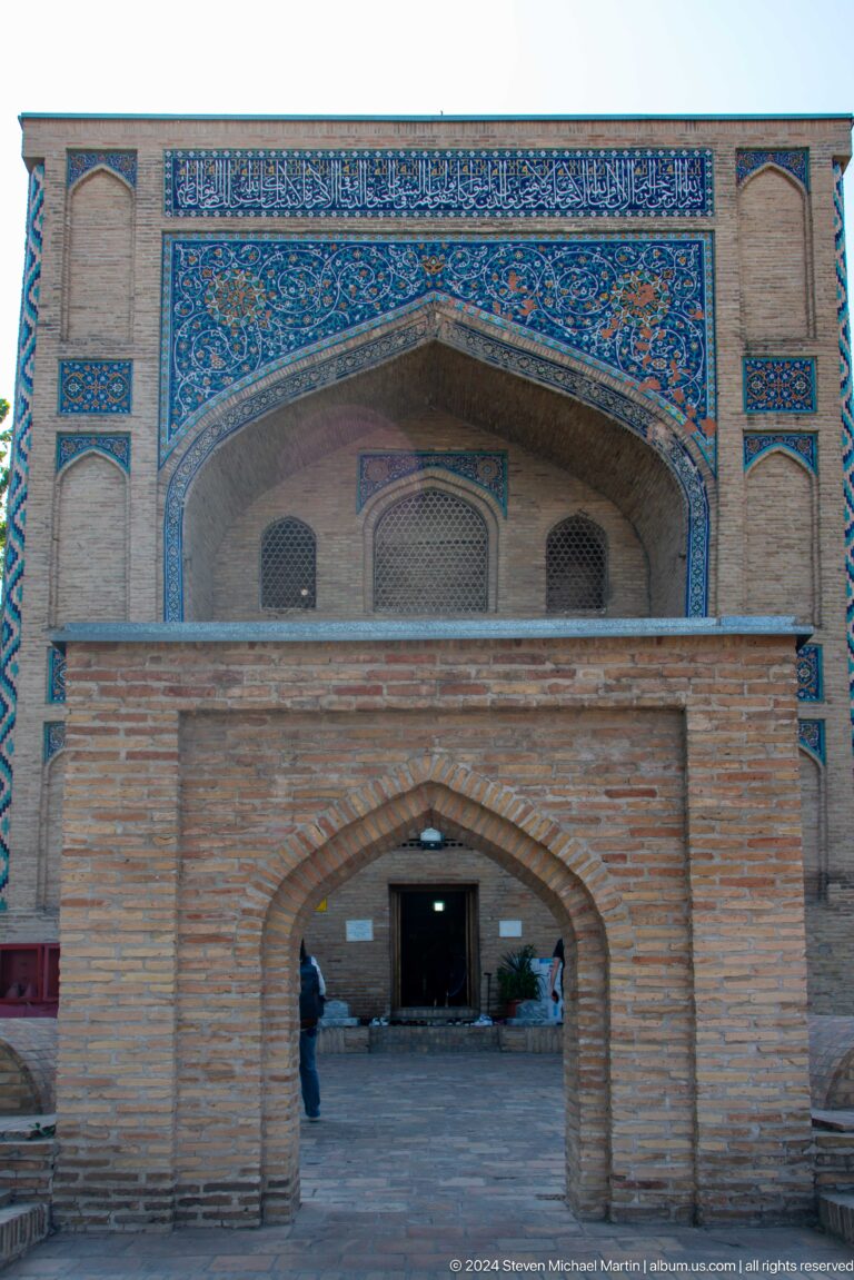Pointed brick arch set beneath a larger tiled facade recess at the Khast Imom complex in Tashkent.