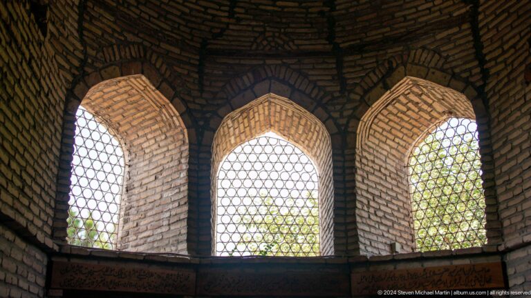 Three pointed arches filled with geometric lattice screens and backlit foliage at the Khast Imom complex in Tashkent.