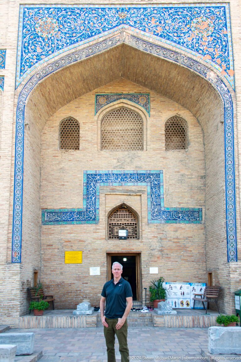 Small pointed doorway framed by stepped turquoise-blue inscription bands at the Khast Imom complex in Tashkent.