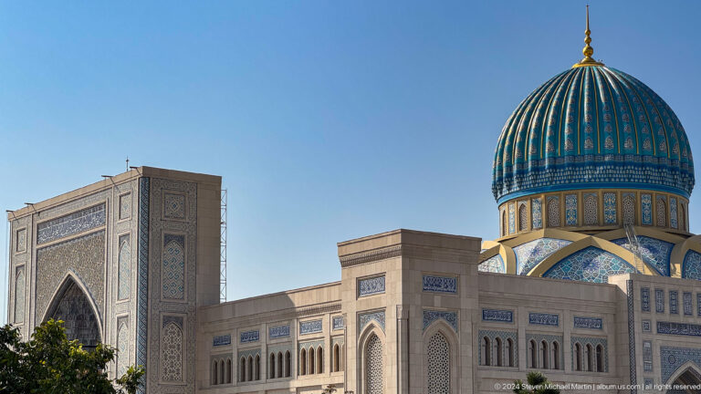 Pale modern facade with monumental portal and striped turquoise dome at right at the Khast Imom complex in Tashkent.