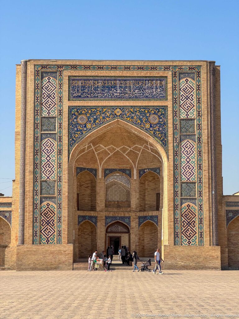 Close frontal crop of tall tiled pishtaq, brick arch, and geometric side panels at the Khast Imom complex in Tashkent.