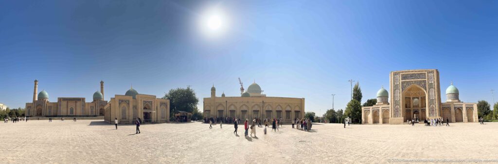 Sunlit paved plaza with several historic religious buildings and scattered visitors at the Khast Imom complex in Tashkent.