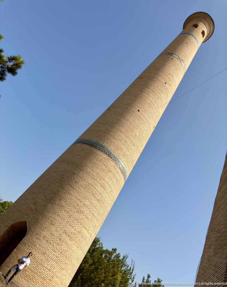 Diagonal pale-brick shaft with narrow turquoise decorative band against blue sky at the Khast Imom complex in Tashkent.