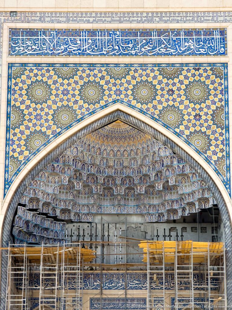 Pointed portal filled with layered cream-and-blue muqarnas and geometric tilework at the Khast Imom complex in Tashkent.