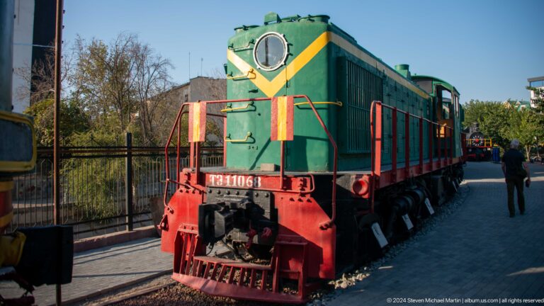 Green diesel shunter with yellow chevron, round front window, red pilot, and side ventilation grilles.