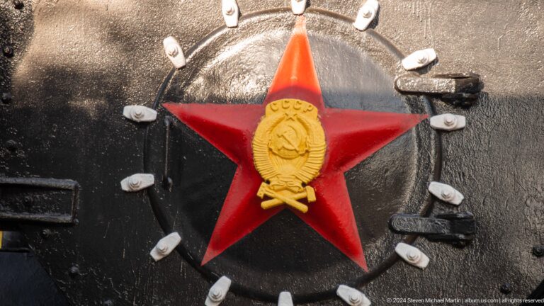 Close-up of a red Soviet star and gold emblem mounted on a black locomotive smokebox.