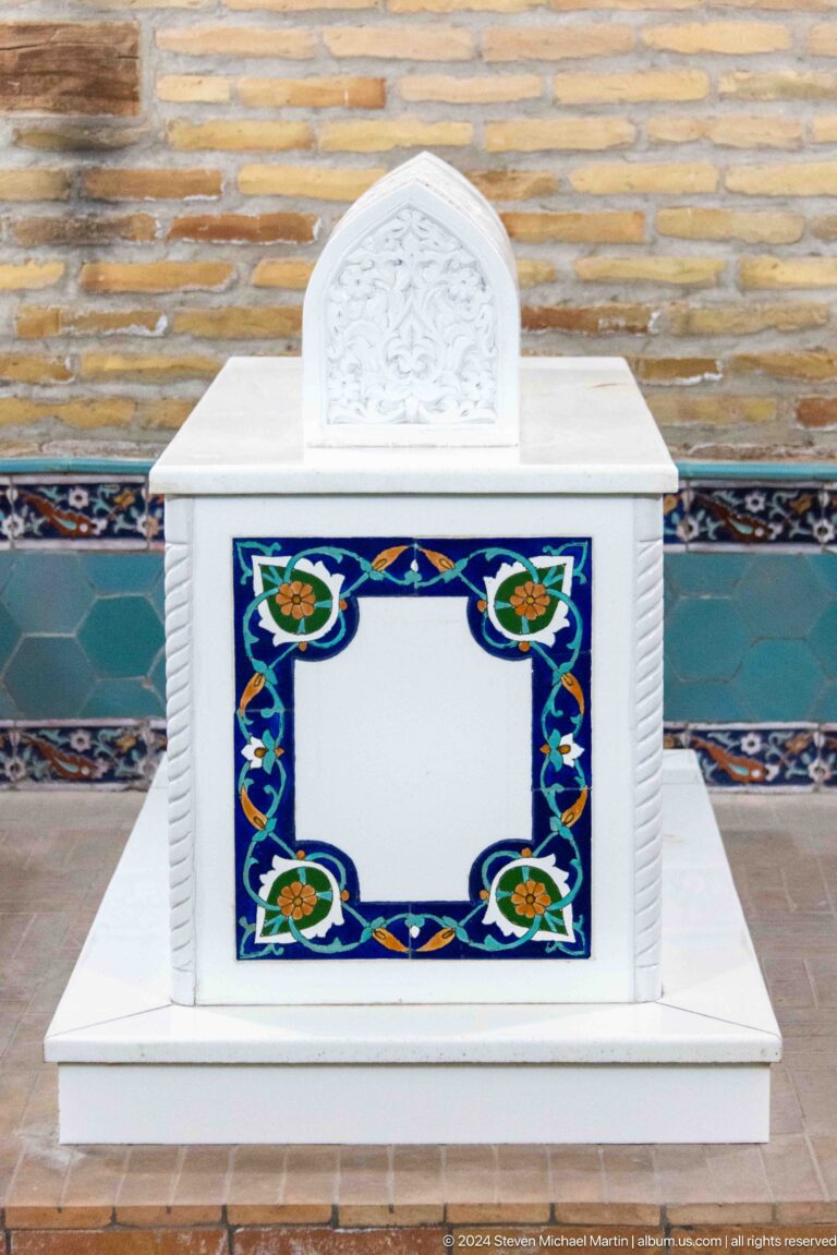 White cenotaph panel bordered by blue floral tiles with orange rosettes.