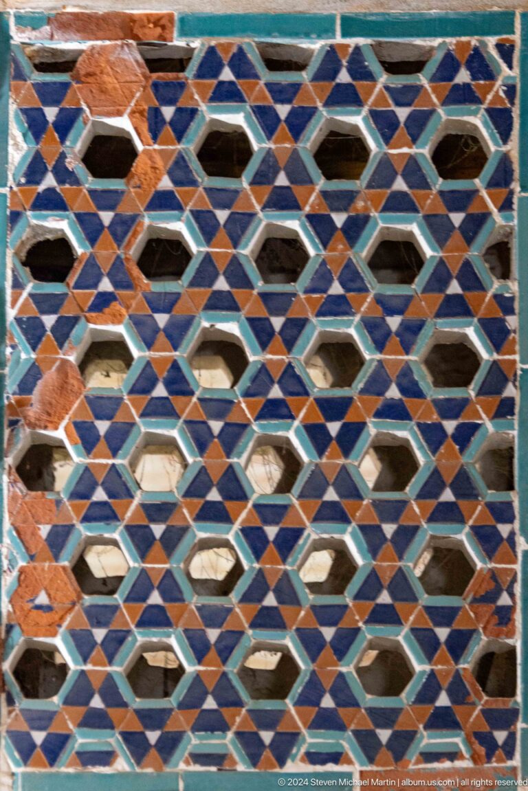 Polychrome ceramic lattice with hexagonal openings and blue, brown, turquoise, and white triangles.