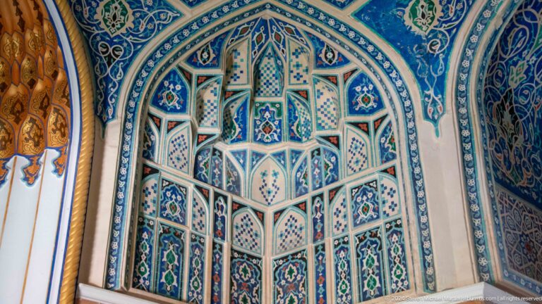 Blue tiled pointed niche with faceted geometric projections and symmetrical floral panels.