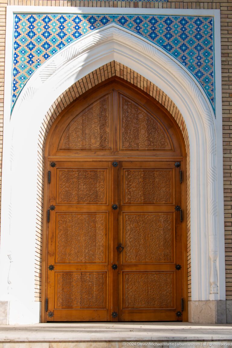 Carved brown double door beneath a pointed arch with pale layered molding.