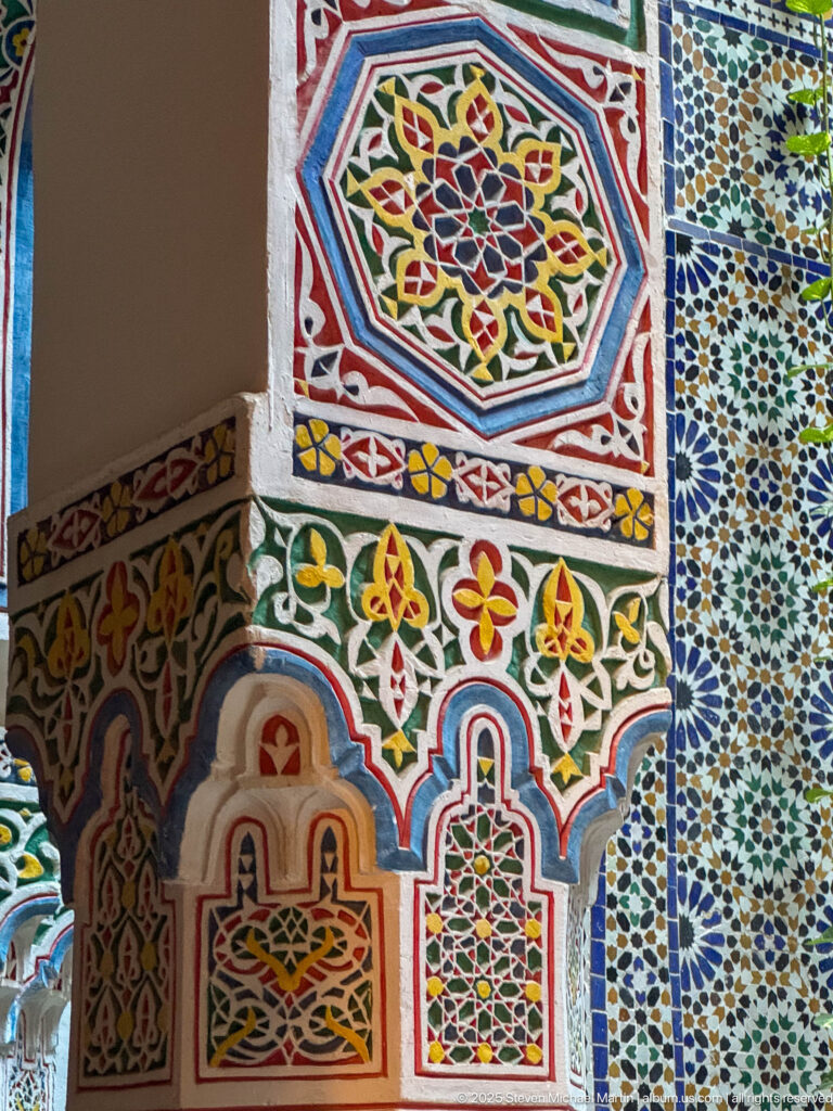 Polychrome painted plaster with arches, floral-geometric motifs, and a strip of zellij at right.