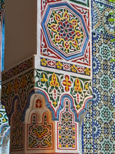 Polychrome painted plaster with arches, floral-geometric motifs, and a strip of zellij at right.