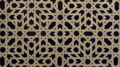 Close-up of pale interlaced geometric bands forming stars and polygons against a dark background.
