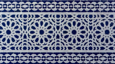 Close view of blue-and-white zellij arranged in repeating rosettes, stars, and angular geometric bands.