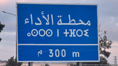 Blue roadside sign with white Arabic lettering and a 300 m distance marker near Fes.