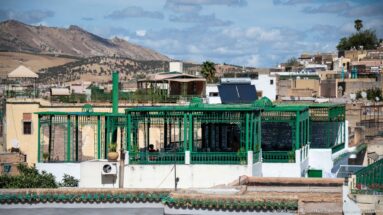 Green-painted rooftop pavilion with metal latticework and terraces above the dense rooftops of Fes.