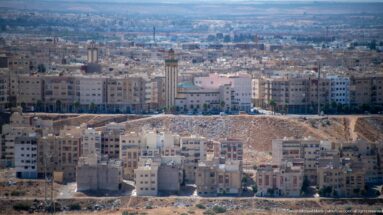 Modern apartment blocks and construction zones on the outskirts of Fes, with a tall tower and dense development beyond.