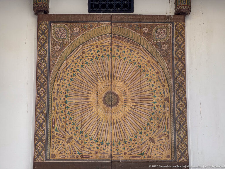 Nineteenth-century decorated wooden main door to Al Batha Palace’s throne hall, in a frontal view centered on its large radiating rosette.