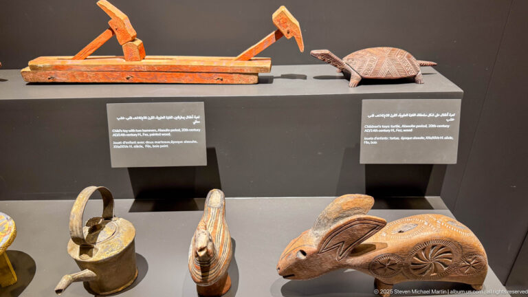 Carved wooden objects including a large animal-shaped form with rosette decoration, smaller handled pieces, and elongated implements.