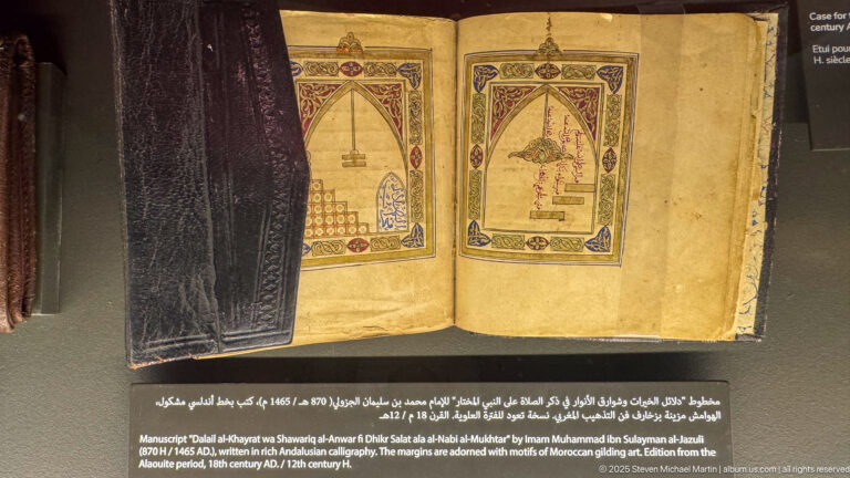 Open Dala'il al-Khayrat manuscript with two framed devotional diagrams, architectural forms, hanging lamps, and colored Arabic inscriptions.