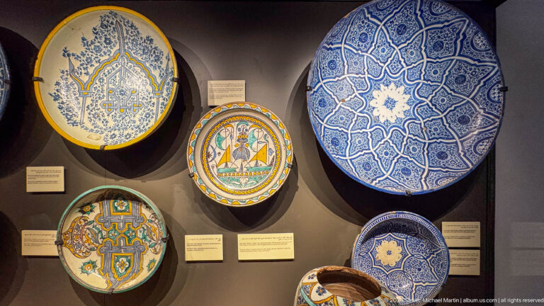 Group of Fes ceramic dishes, including an early-19th-century blue-and-yellow plate with a mihrab motif and mirrored Arabic inscription.