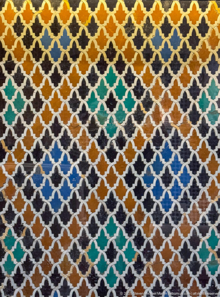 Close detail of fourteenth-century Marinid zellij with black, amber, turquoise, blue, green, and white cut tiles.