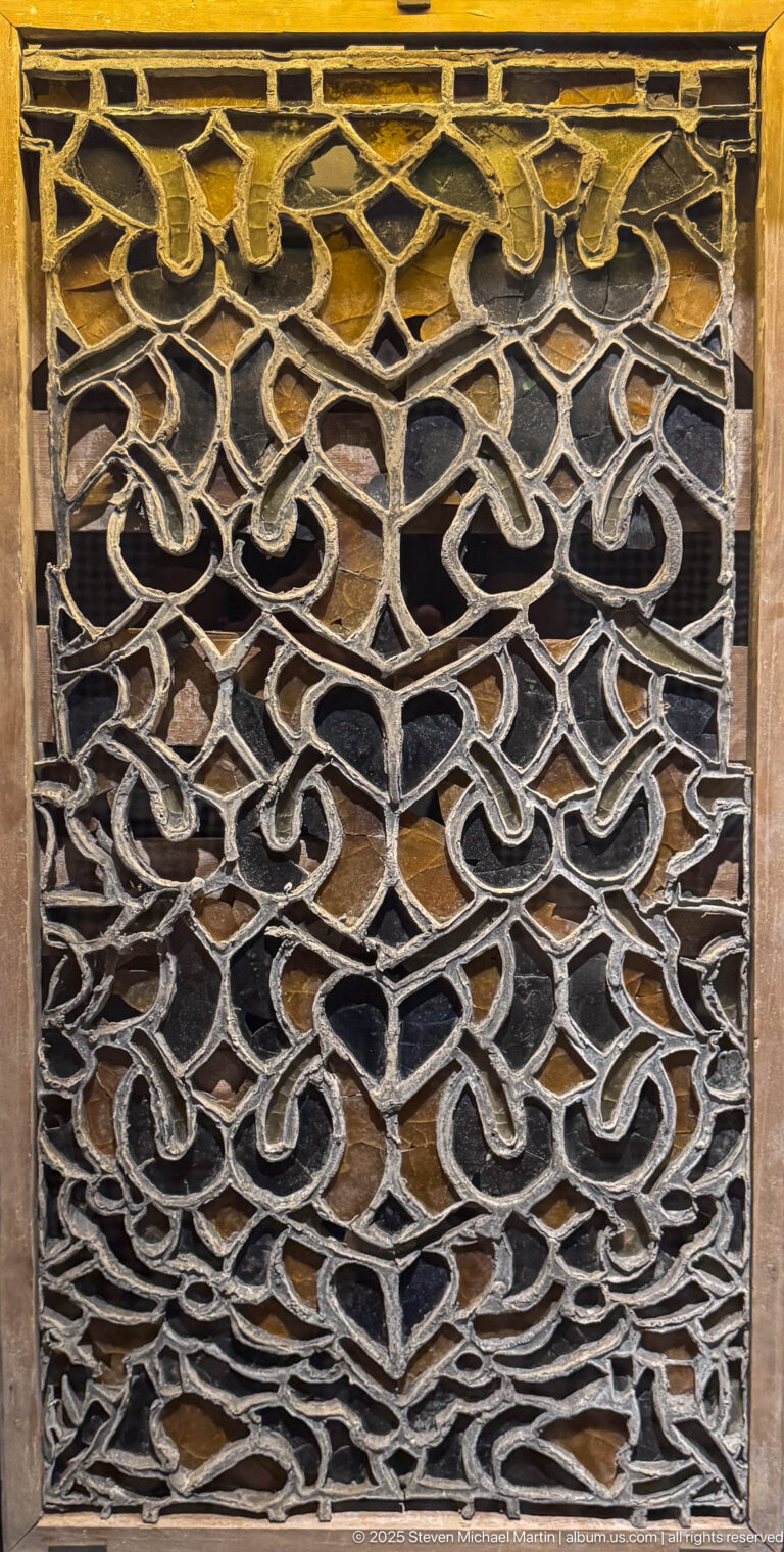 Square wooden panel with dense interlaced geometric carving forming small polygonal openings.